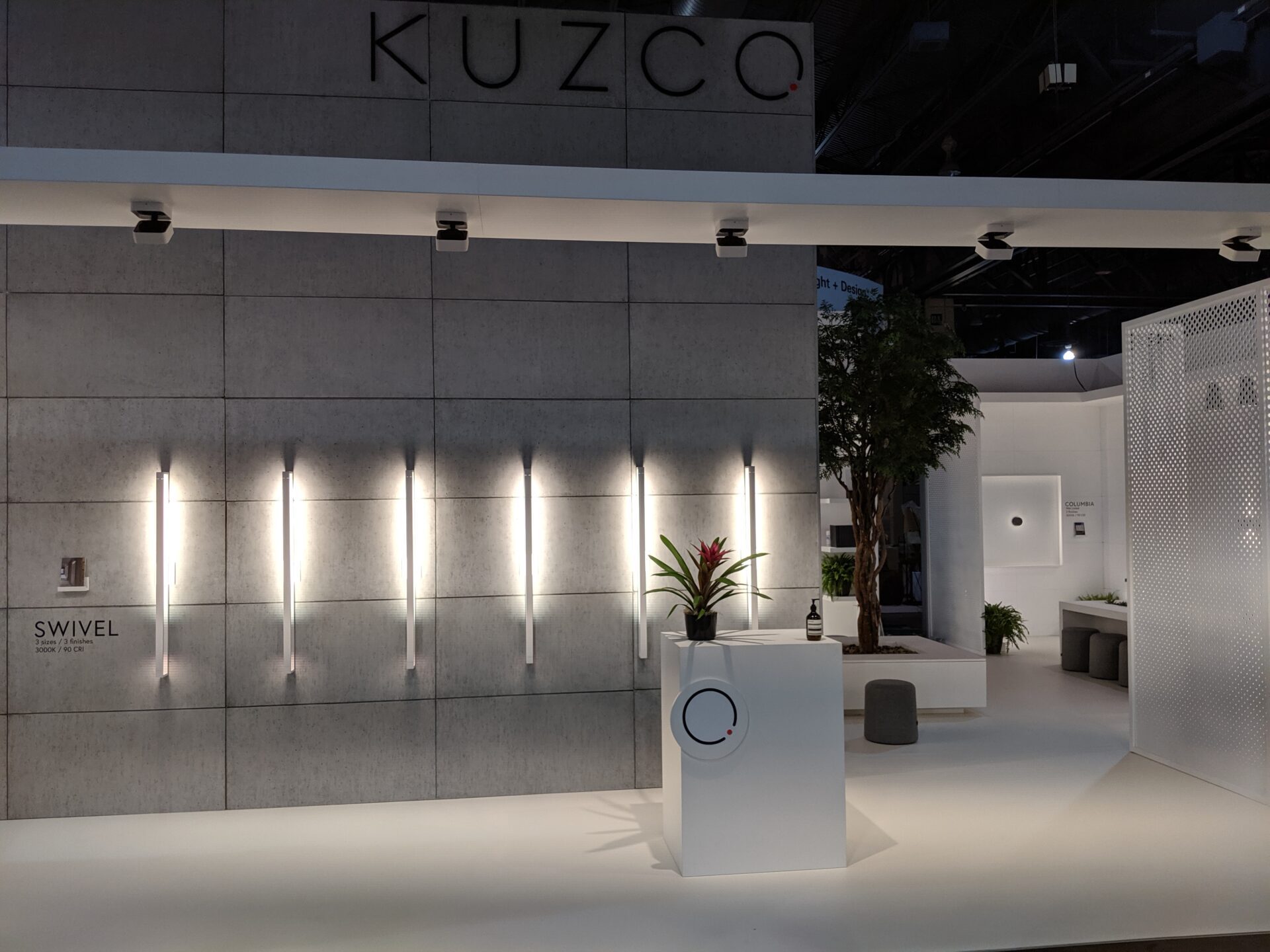 Kuzco trade show booth with greenery and upscale fabric seeting