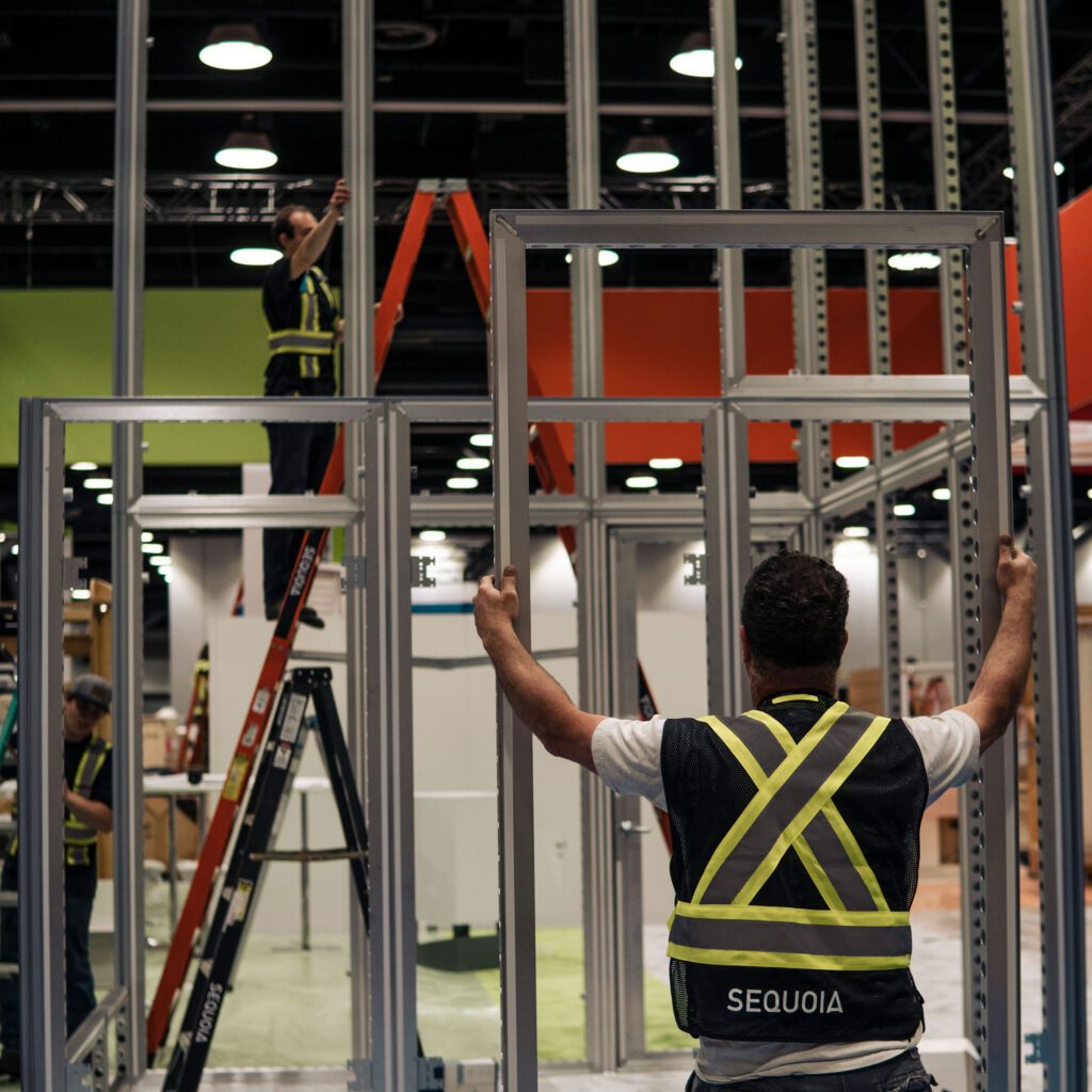 Man holding up metal door frame while setting up trade show booth