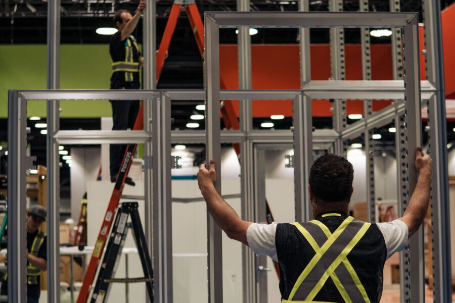 Man holding up metal door frame while setting up trade show booth