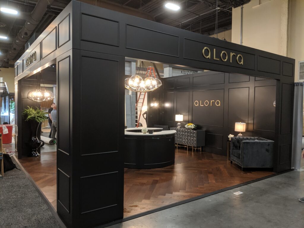 Alora trade show booth with black paneling and upscale seating